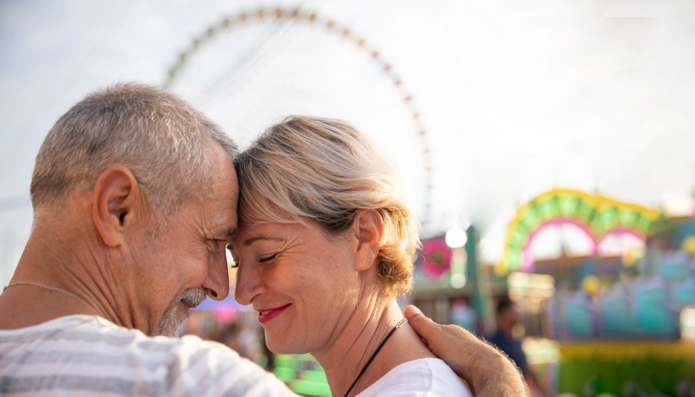 Ein Paar über 50 begegnet sich lächelnd auf einem Jahrmarkt